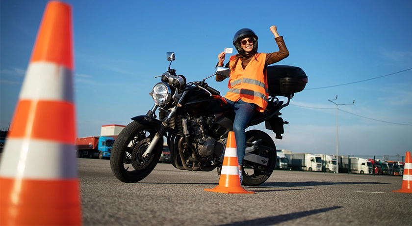 Young rider on a motorcycle holding her bike licence.webp