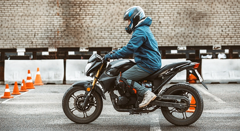 young rider sitting on a motorcycle next to cones.webp